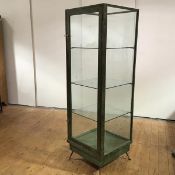 A freestanding display cabinet, the wooden frame with simulated verdigris finish and cast-brass