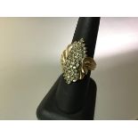 A diamond cluster ring, set with claw-set lines of diamond points within scrolling reeded shoulders,