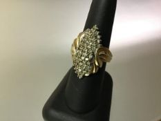 A diamond cluster ring, set with claw-set lines of diamond points within scrolling reeded shoulders,