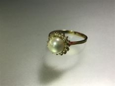 A cultured pearl and diamond cluster ring, the central pearl (approx. 6mm diameter) within a band of