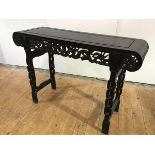 A Chinese hardwood altar table, early 20th century, the incised rectangular top with scroll ends and