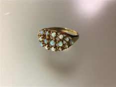 An opal cluster ring, the three bands of small opal cabochons claw set on a yellow metal tapering