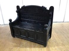 A late 19th century ebonised hall settle, the arched back with Gothic fret frieze carved with