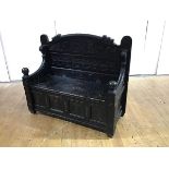 A late 19th century ebonised hall settle, the arched back with Gothic fret frieze carved with