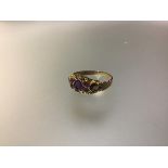 An amethyst cluster ring, centred by an oval-cut stone flanked by pairs of round-cut stones, the