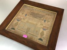 An early 19th century needlework sampler, worked in polychrome threads with alphabet, urns of