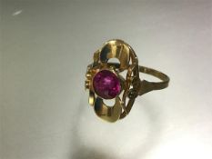 A single stone ruby ring, the round-cut stone centred on a modernist pierced shaped mount, on a