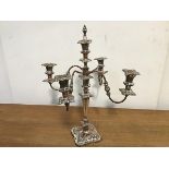 A silver plate on copper candelabrum, with four scrolling branches radiating from a central stem,