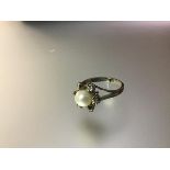 A cultured pearl and diamond cluster ring, the central pearl (approx. 7mm diameter) within a band of