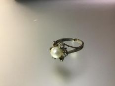 A cultured pearl and diamond cluster ring, the central pearl (approx. 7mm diameter) within a band of