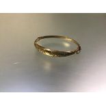 A 9ct yellow gold bangle, hinged, the hollow tapering band scroll-engraved, hallmarked for Chester