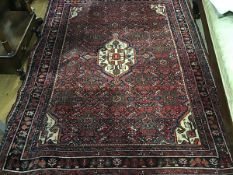 A North-West Persian rug, the central ivory medallion within a madder field decorated with