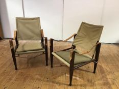 A pair of safari chairs, each with stitched canvas back and seat and strap arms, united by turned