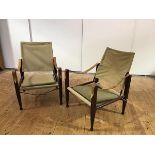 A pair of safari chairs, each with stitched canvas back and seat and strap arms, united by turned