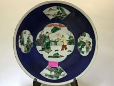 A Chinese porcelain dish, decorated with famille rose cartouches against a powder blue ground, the