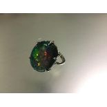 A striking and large single stone opal ring, the oval-cut Lightning Ridge black, five colour opal