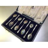 A cased set of eight silver and enamel coffee spoons, Birmingham 1958, each bowl decorated to the