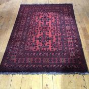 A modern Afghan rug with two indigo framed medallions within a madder field decorated with