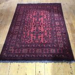A modern Afghan rug with two indigo framed medallions within a madder field decorated with