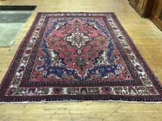 A Tabriz-style carpet, the central medallion with scalloped edge within a madder field decorated