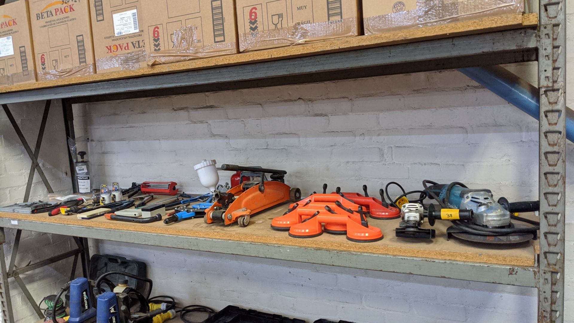 Contents of a shelf of assorted tools including Makita small & large angle grinders, suction