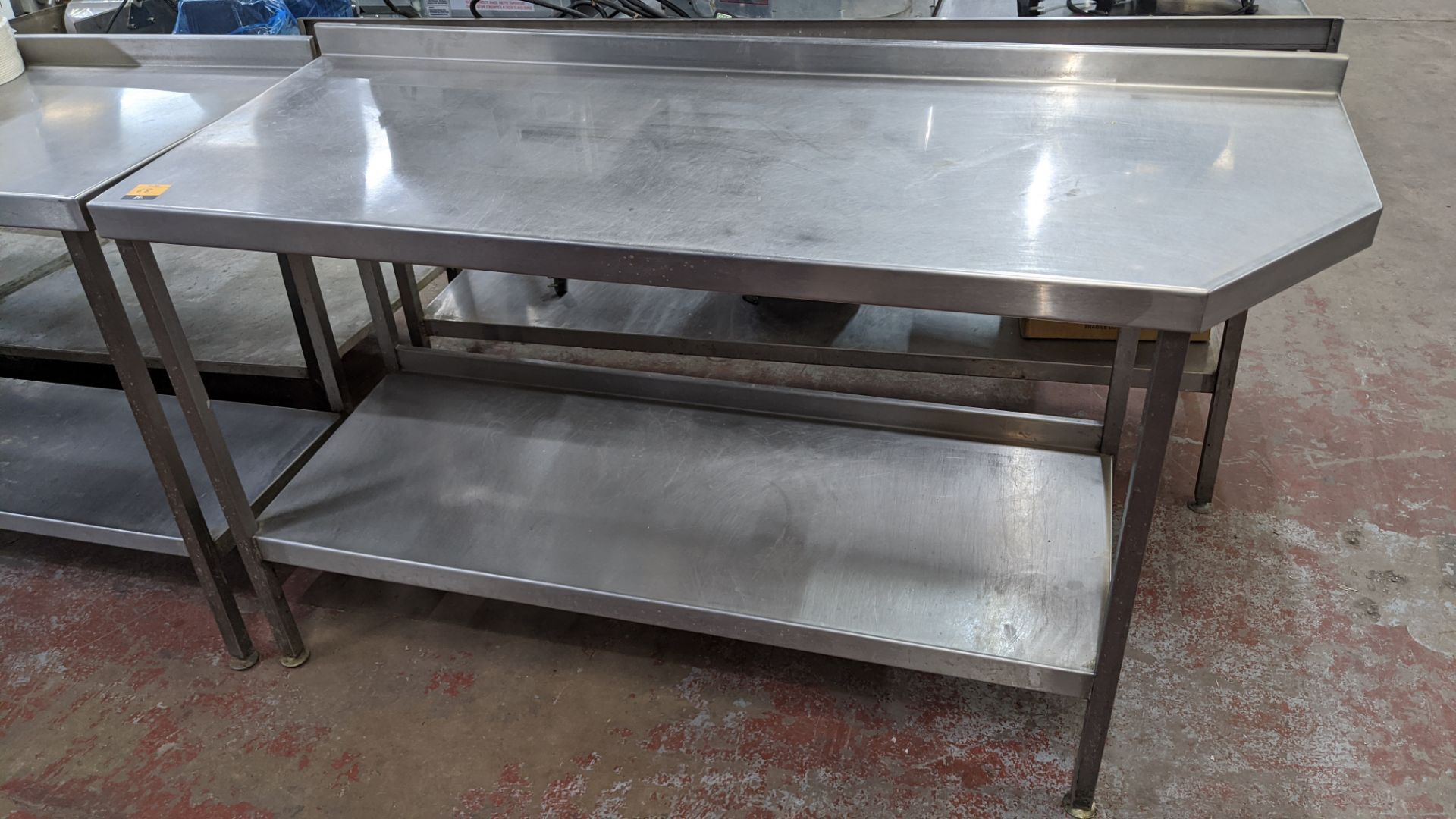 Stainless steel twin tier table with top measuring approximately 1600mm x 600mm at extremes (please - Image 2 of 3