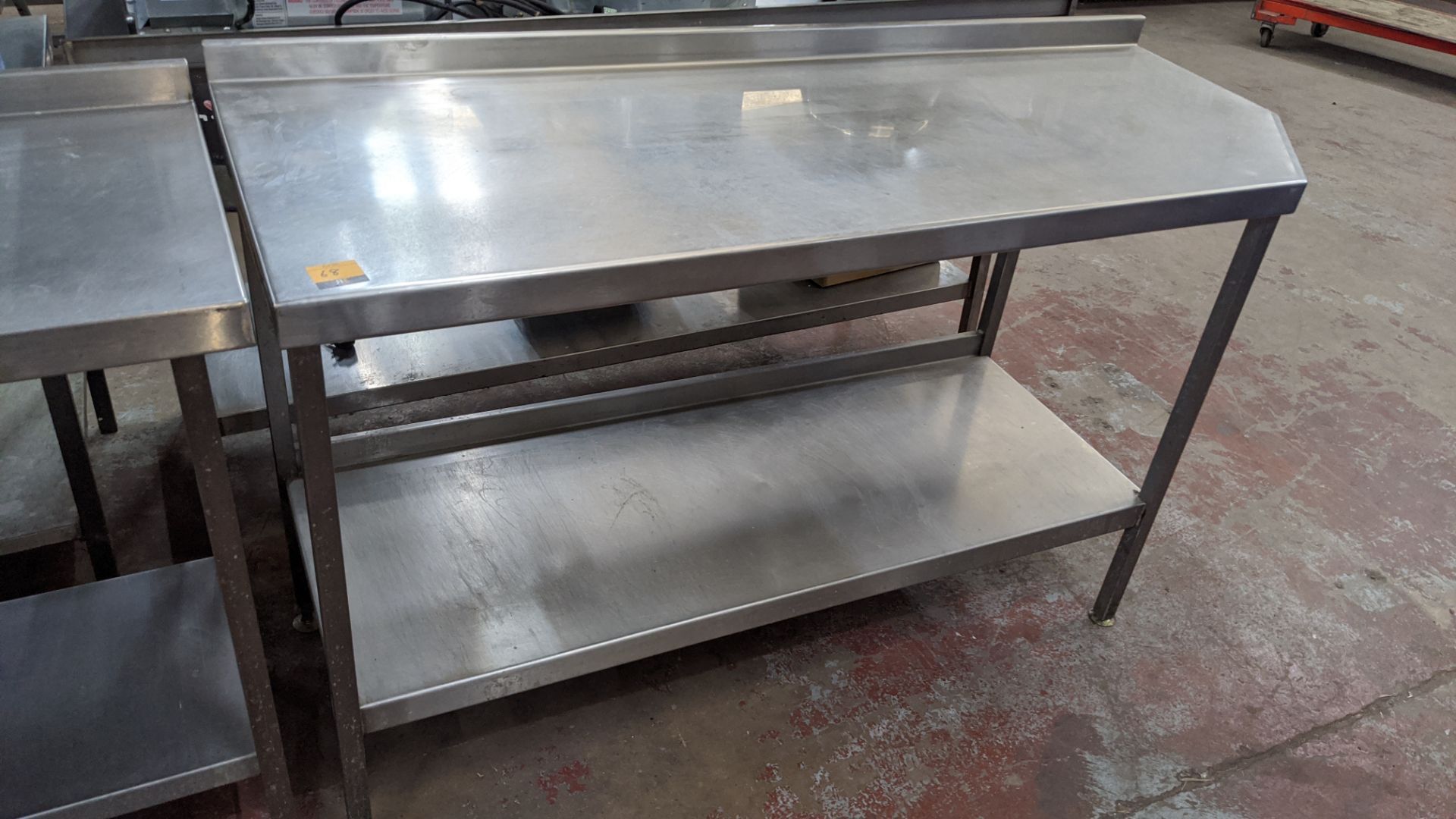 Stainless steel twin tier table with top measuring approximately 1600mm x 600mm at extremes (please