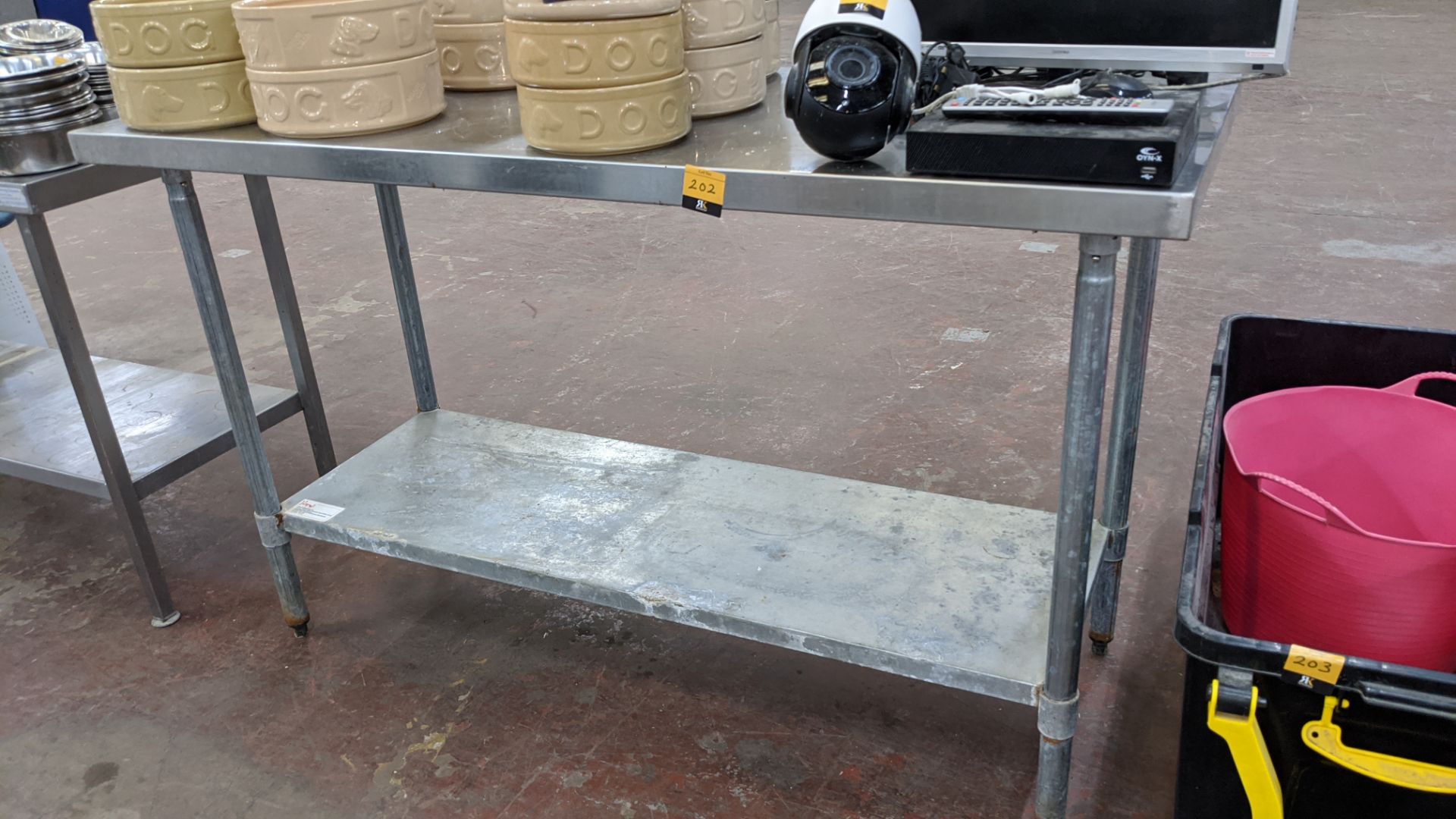 Twin tier stainless steel table measuring approximately 60" length, 24" depth, 36" height