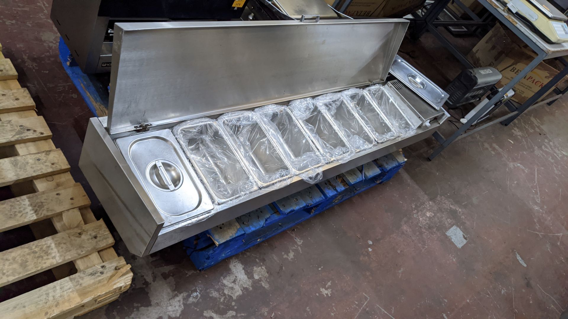 Large stainless steel countertop saladette unit including what appear to be brand new trays for use