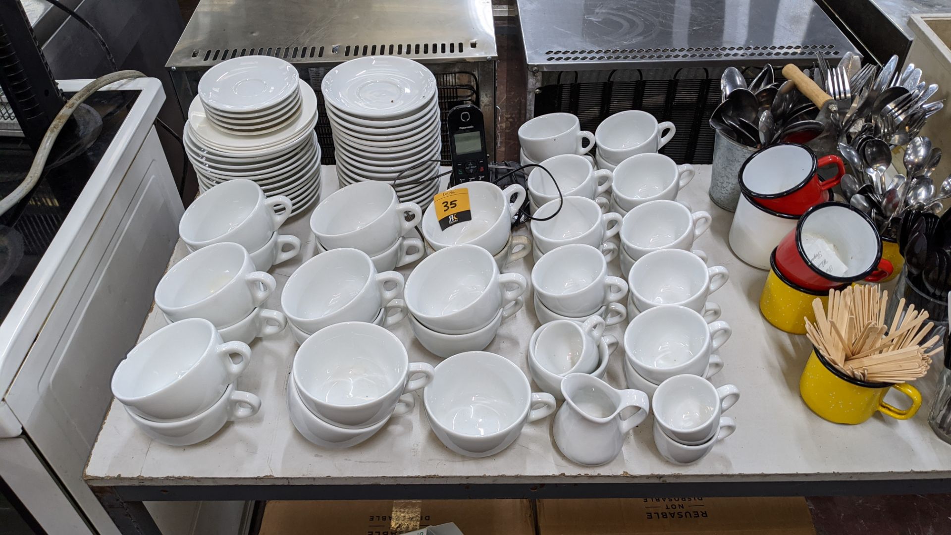 The contents of a table comprising white cups & saucers plus cutlery, utensils, chopping boards, min - Image 3 of 6