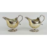 PAIR OF LATE VICTORIAN SILVER CREAM JUGS raised on scroll design pedestal with loop handle and