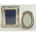 TWO MODERN SILVER PHOTOGRAPH FRAMES, plain oval and embossed rectangular, largest 13cms high (2)