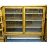 OAK SLIDING DOOR BOOKCASE with interior adjustable shelves and glazed front on tapering supports,