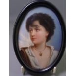 PAINTED PORCELAIN PORTRAIT MINIATURE of a young girl, oval format, in an ebonized frame, 14 x 10.
