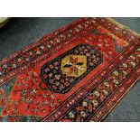 CAUCASIAN NARROW RUG with hexagonal medallion to red field, floral spandrels, serrated leaf border