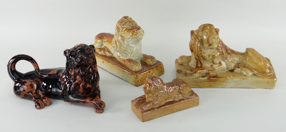 THREE SALTGLAZED POTTERY LIONS of recumbent form on plinths, largest 22cms wide, and a pottery