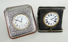 TWO GOLIATH WATCHES IN MOUNTED TRAVEL FRAMES, one with Asian white metal surround, 6cms diameter