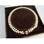 TWIN-STRAND PEARL NECKLACE with 9ct yellow gold ruby and gold clasp, 57.8grams in velvet lined box