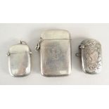 THREE SIMILAR SILVER VESTA CASES, one florally engraved, one with initials and one plain. All
