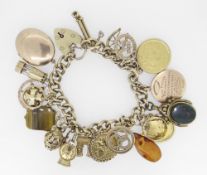 9CT YELLOW GOLD CURB LINK CHARM BRACELET HAVING HEART SHAPED PADLOCK and assorted coins and charms