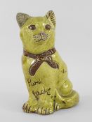 EWENNY POTTERY MODEL OF A SEATED CAT in mottled yellow glaze, unglazed bow and eyes, incised