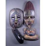 FOUR CARVED TRIBAL WALL MASKS, the majority having colourful beadwork decoration