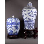 TWO ORIENTAL BLUE & WHITE STORAGE JARS on carved hardwood stands decorated with peonies and a