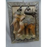 A LARGE BURMESE CARVED ELEPHANT with 3 riding figures on a carved framed panel, 57x78 cms