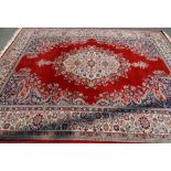 SUPER KESHAN RED GROUND CARPET classically patterned with tasselled ends, 275 x 365cms