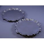 SILVER SALVERS, a pair, each of plain form with wavy rims on 3 scrolled feet, 25cms diameter, 36ozs,