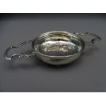SILVER LEMON STRAINER with twin leaf form handles and star pattern pierced base of Georgian style,