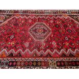 VINTAGE IRANIAN WOOL CARPET - red ground with traditional central motif and multi-bordered edge, 270