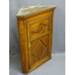 ANTIQUE OAK CORNER HANGING WALL CUPBOARD with single two panel door and applied beading, opening