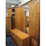 MODERN PINE FOUR PIECE BEDROOM SET of two triple wardrobes with central mirrored doors on multi-